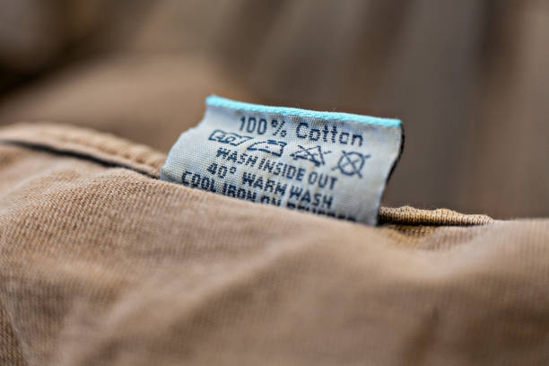 Close-up of a care label on a cotton garment with washing instructions, highlighting "100% Cotton."